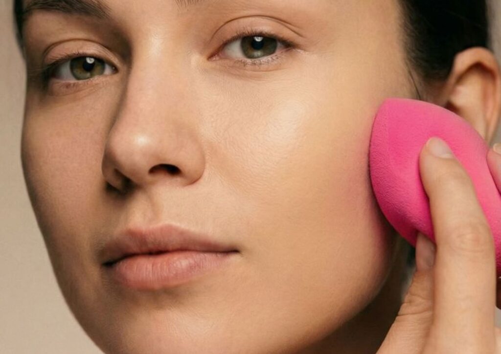 Blending foundation evenly with a makeup sponge for a seamless finish